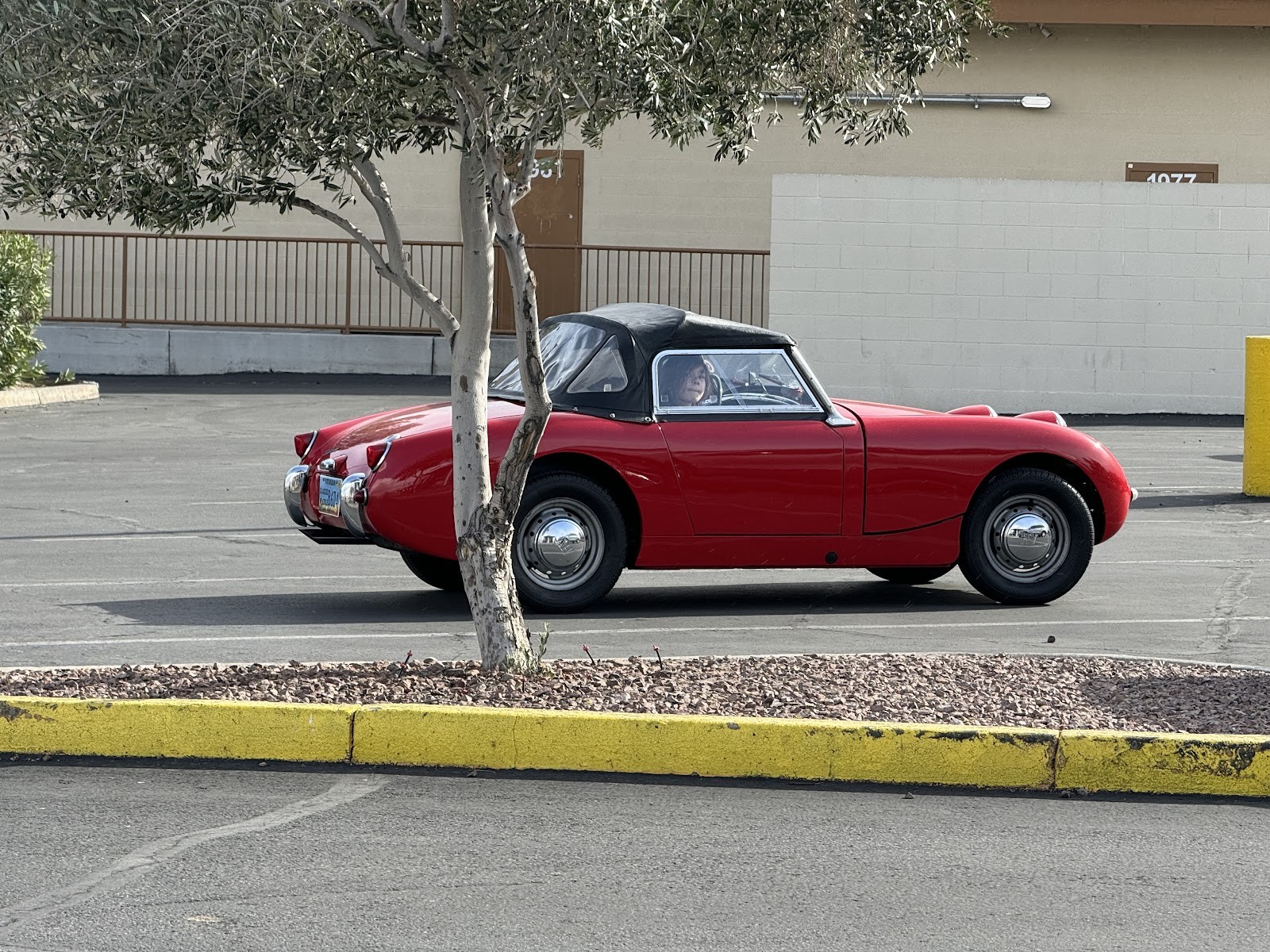 Restored red classic Austin-Healey Sprite convertible in a parking lot